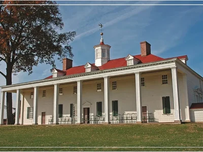 A historic building with a red roof and white columns set against a clear blue sky
