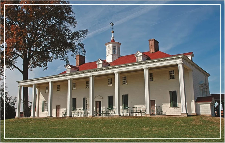 A historic building with a red roof and white columns set against a clear blue sky